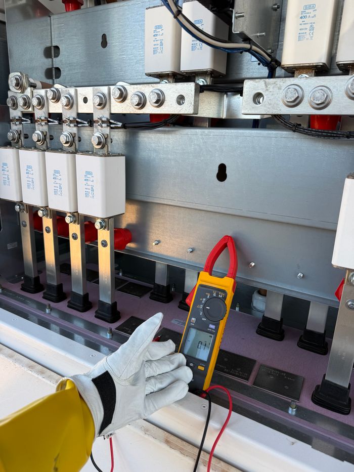 About Technician using multimeter to measure voltage in an electrical panel. Professional outdoor maintenance.